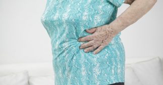 Older woman holding her stomach.