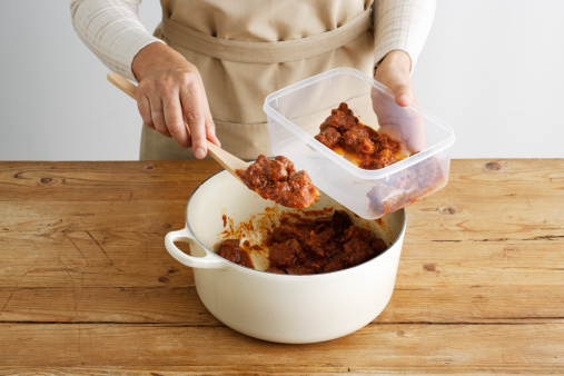 Woman spooning meat into tupperware