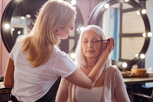 Womans personal stylist applying mascara to her eyelashes