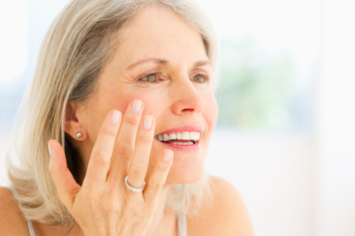 USA, New Jersey, Jersey City, Portrait of senior woman applying moisturizer
