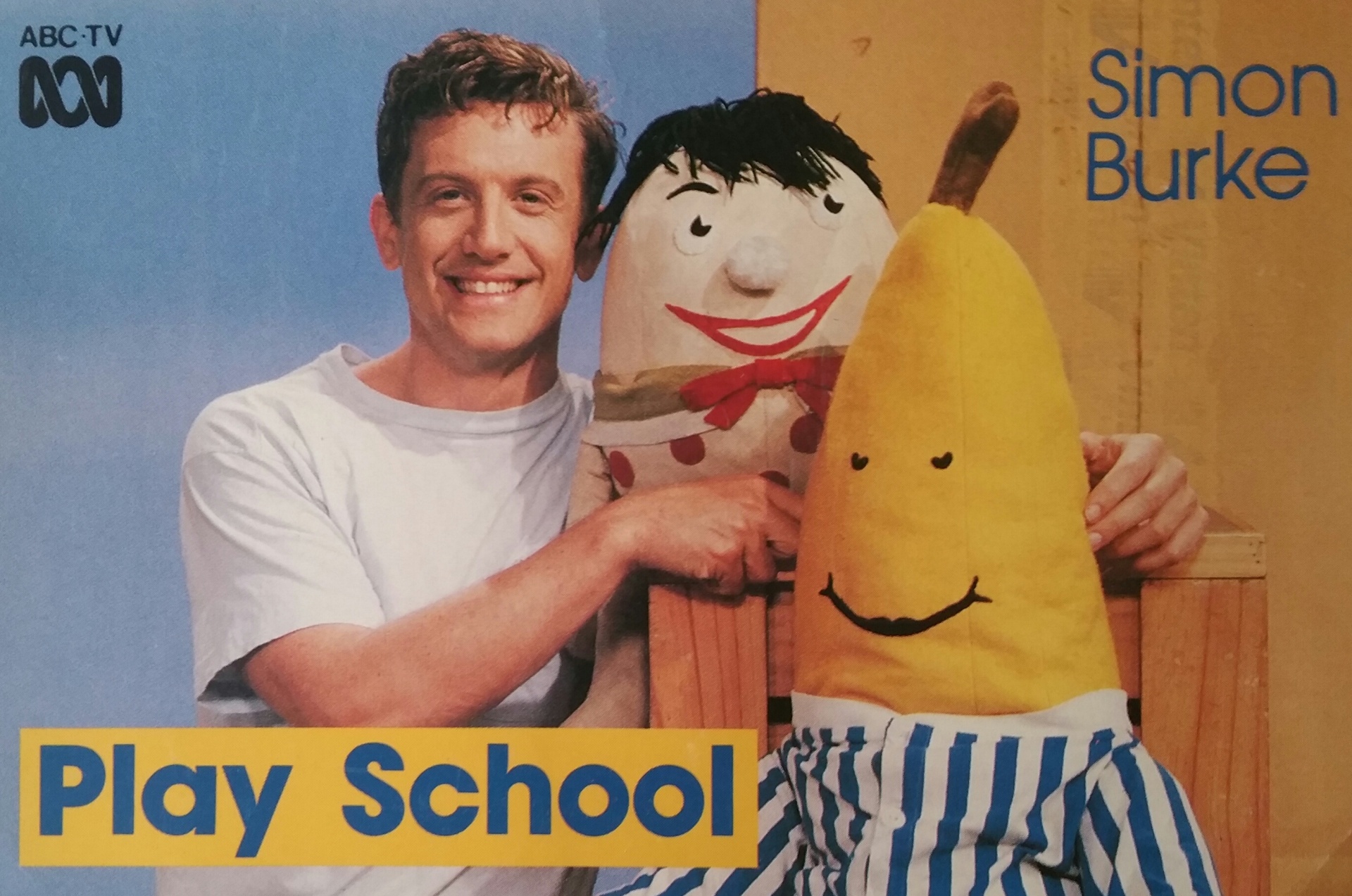 A smiling television presenter poses with two familiar children’s show characters on a promotional poster.