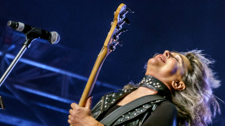 Suzi Quatro playing bass guitar on stage with her head tilted back in a rock performance.