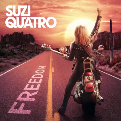 Album cover for Suzi Quatro’s “Freedom” showing her on a motorcycle in a desert road at sunset.