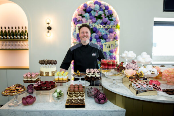 Chef standing behind an elaborate dessert display.
